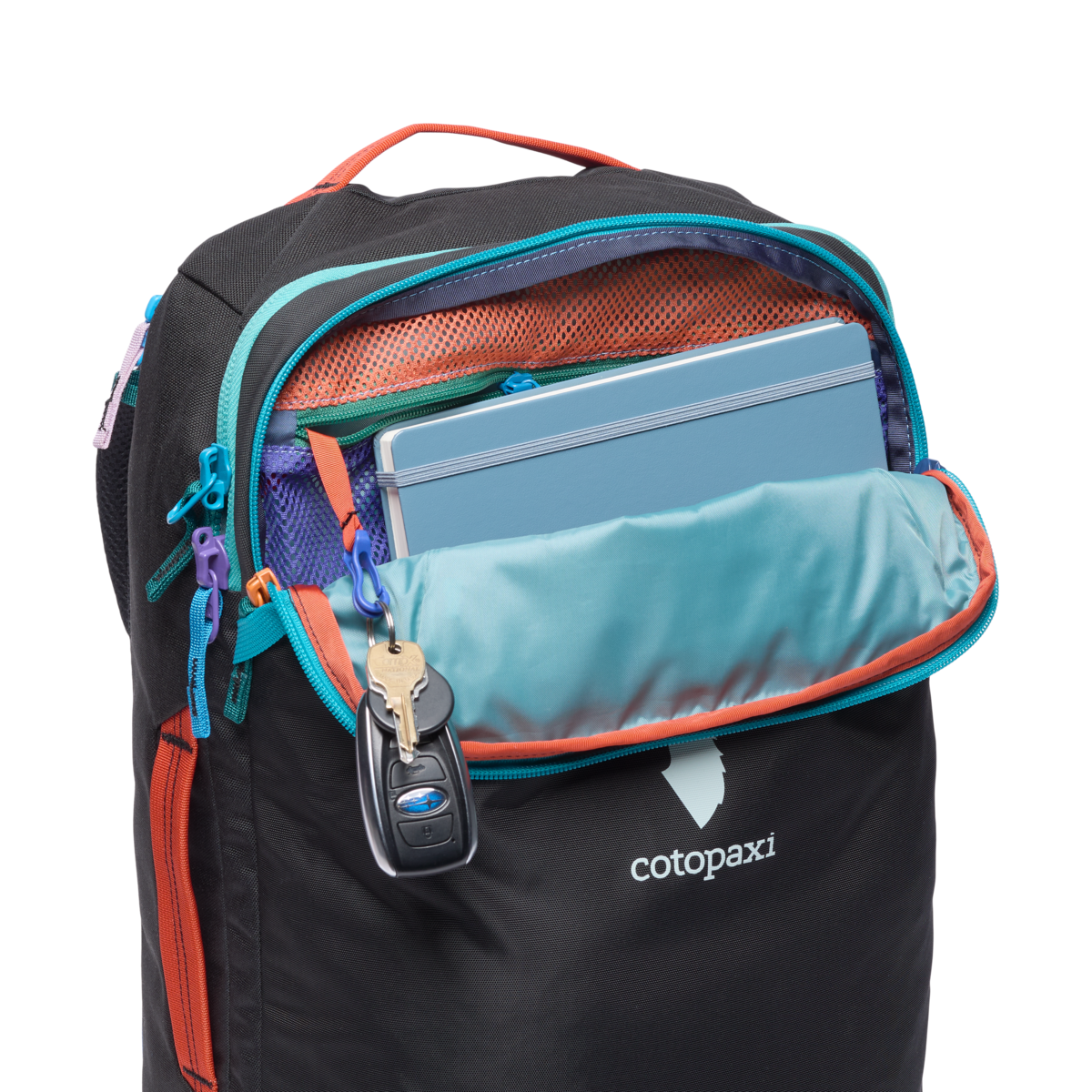 Cotopaxi Allpa 28L Travel Pack in black with an open top compartment showing a blue notebook and keys hanging inside.