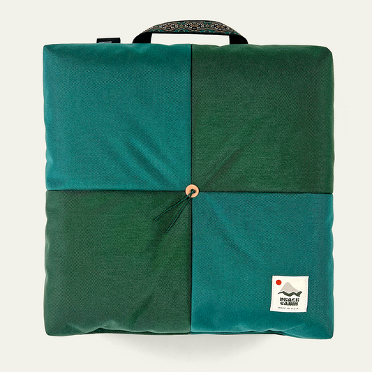Wanderer 'QUAD' Outdoor Cushion by Media Mercantile, featuring a four-panel design in two shades of green with a central toggle and patterned handle.