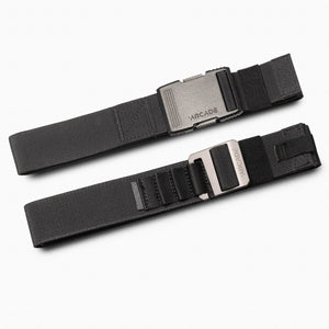 Arcade Twilight Stretch Belt. Two black elastic belts with metal buckles, one gunmetal, one silver, against white.