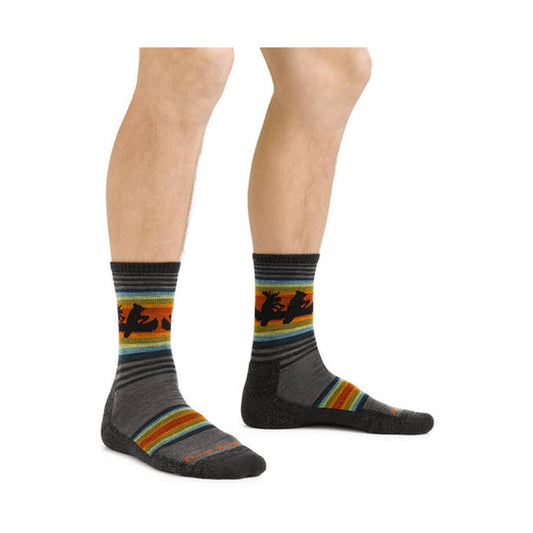 Men's Willoughby Micro Crew Darn Tough socks, grey with colorful stripes and animal designs on a man's legs.
