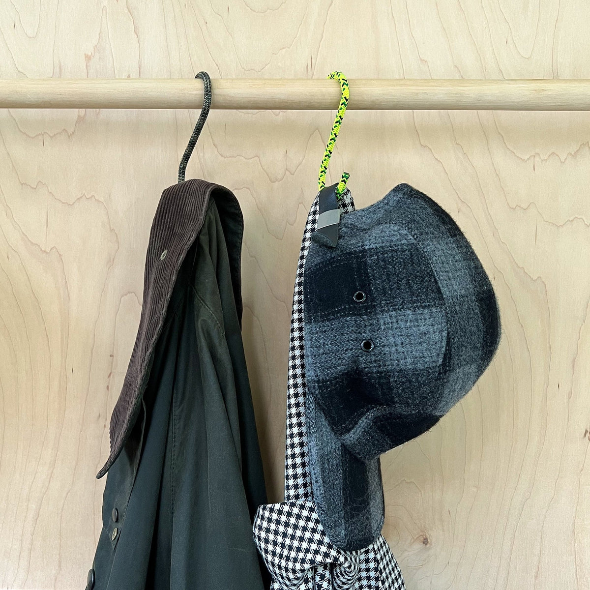 Media Mercantile Utility Hanging Hooks in 4 Pack, featuring a dark jacket and plaid hat hanging on rope hooks from a wooden rod.