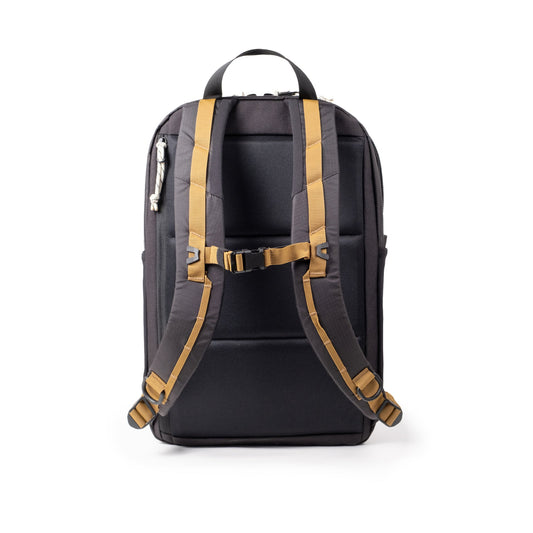 Topo Designs Commuter Backpack, black with tan straps, showing the back with sternum strap and padded back panel