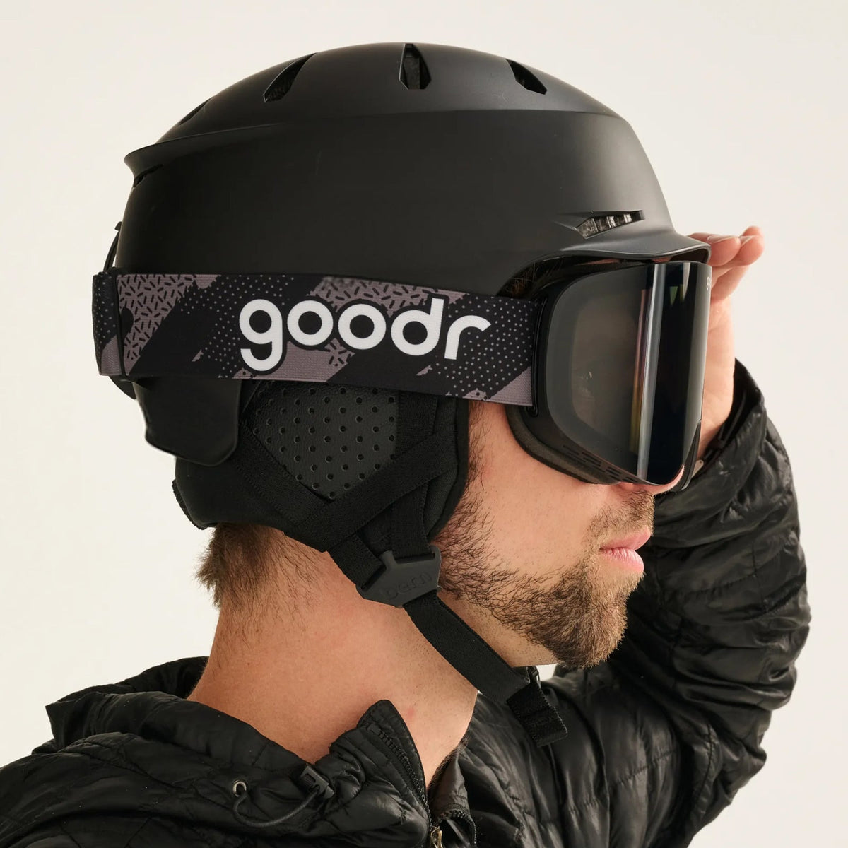 goodr Midnight Snow Society goggles and black ski helmet on a person looking right, against a white background.