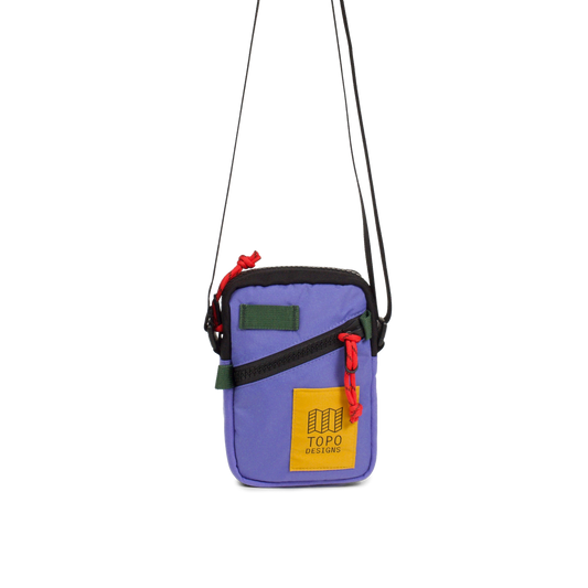 Topo Designs Mini Shoulder Bag in purple with black zipper, green accents, red cord pull, and yellow logo patch.