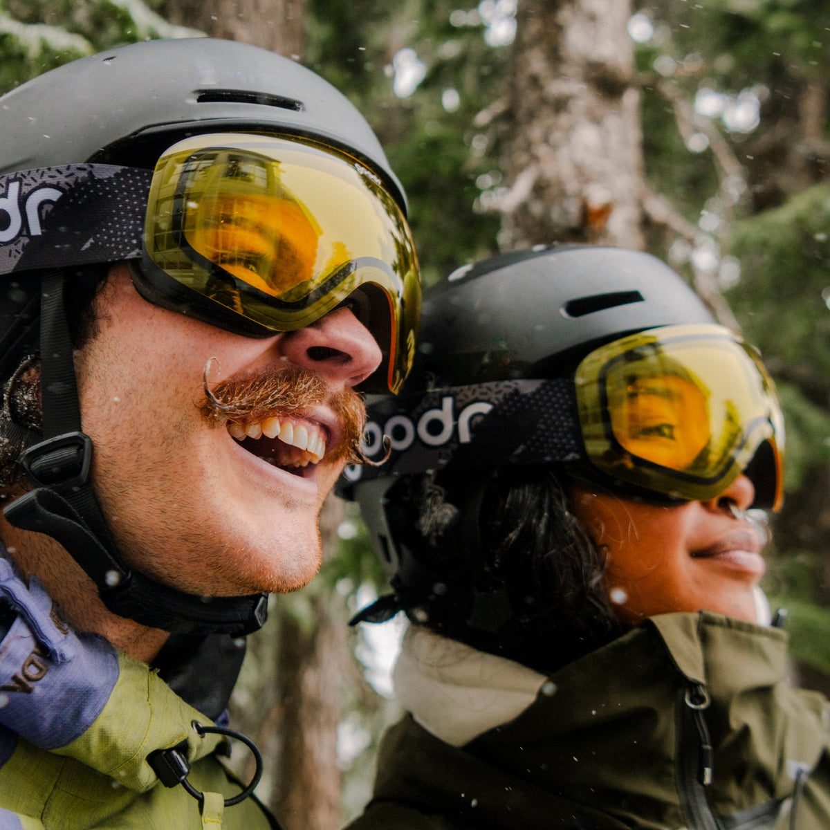 Happy skiers wearing helmets and bright yellow 'Yellow Jacket's Yard Sale | goodr' goggles in a snowy forest.