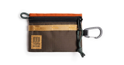 Topo Designs Mountain Accessory Bag in brown, orange, and gold with a black zipper and carabiner, on white.