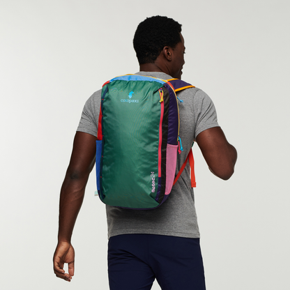 Man wearing a colorful Cotopaxi Batac 24L backpack, green with pink, blue, red, and purple accents, seen from behind.