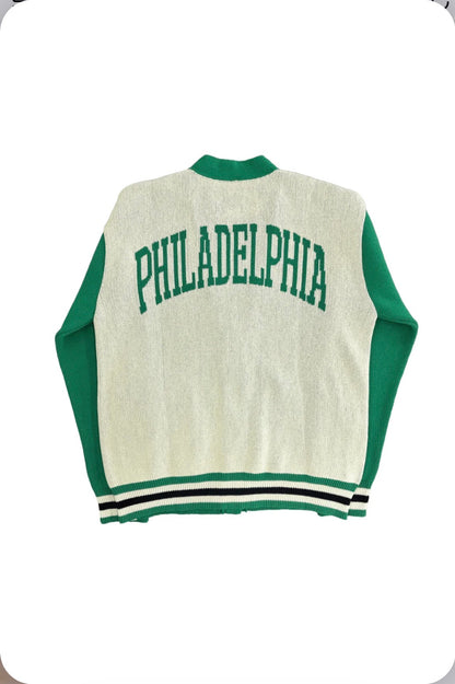Back of Birds Eco Cardigan from Boathouse Sports, cream with green sleeves and 'PHILADELPHIA' in green on the back, striped trim.