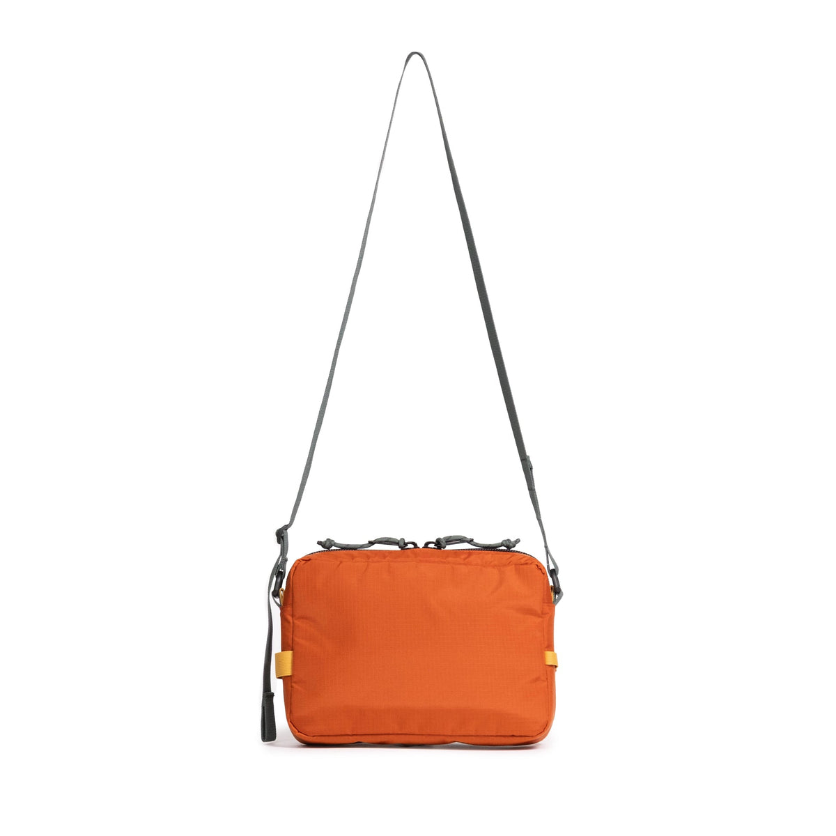 Topo Designs Block Bag in orange with a grey adjustable strap, hanging. Front view of a versatile utility pouch.
