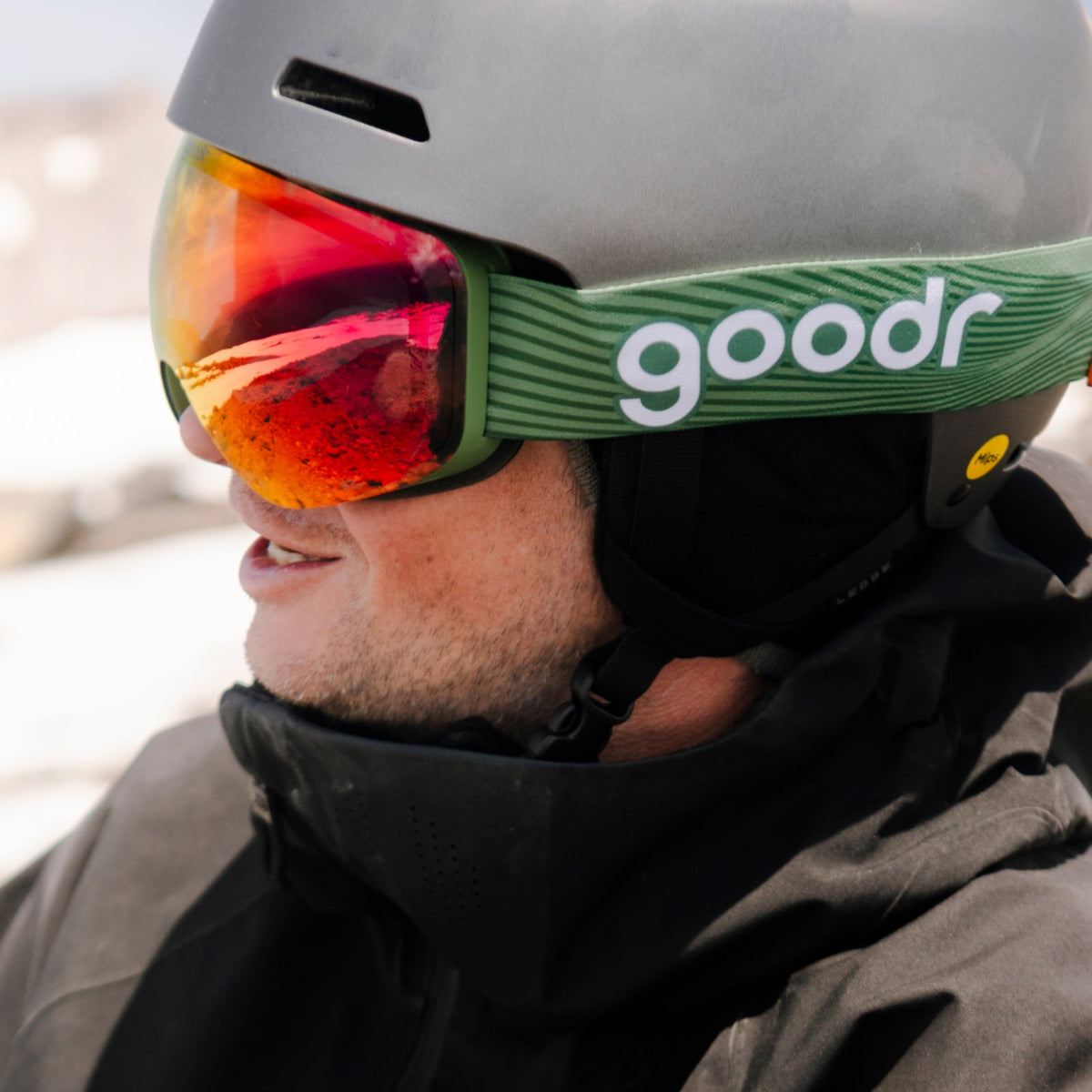 Casual Hot Dogger | goodr goggles with red reflective lenses on a smiling person wearing a grey helmet and black jacket.