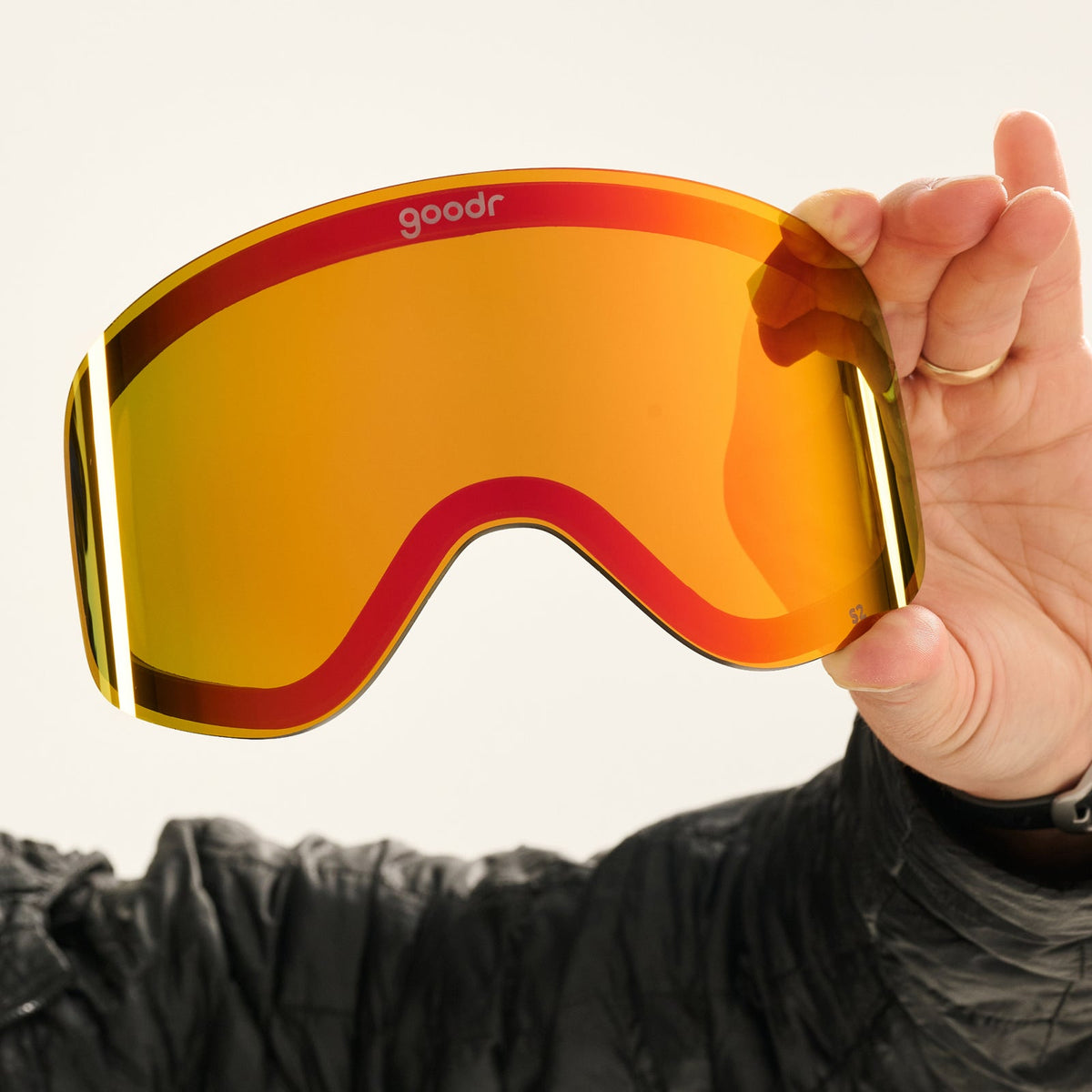 Chili Chill goodr ski goggles with bright orange-red mirrored lenses, held by a hand in a black jacket.