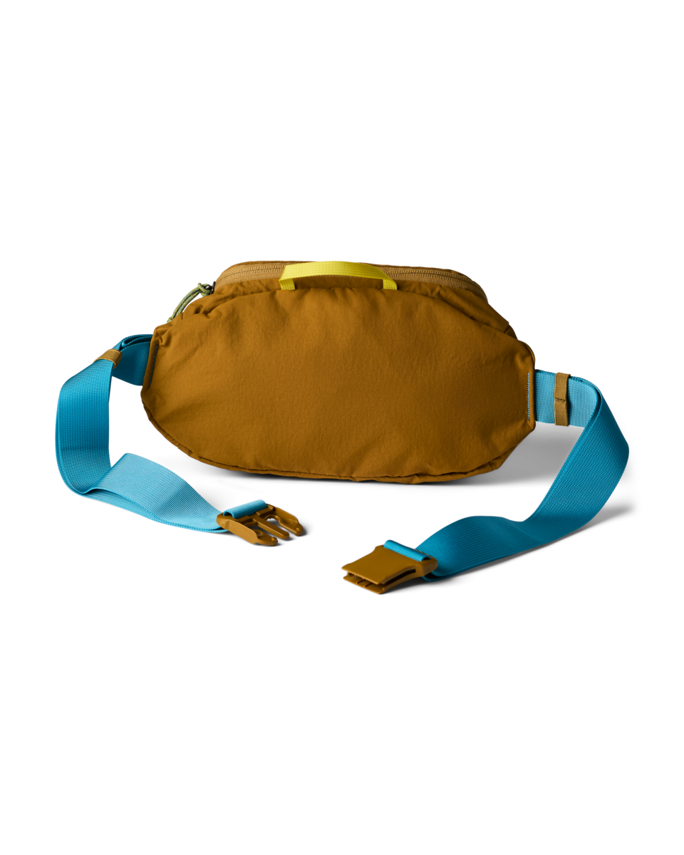 Cotopaxi Empacable 3L Sling in brown with blue strap and yellow handle, unbuckled. Versatile hip pack.