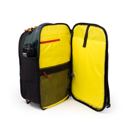 Topo Designs Global Travel Backpack open to show bright yellow interior with mesh and slip pockets, and a water bottle
