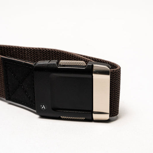 Close-up of the Arcade Motion Stretch Belt in brown, showcasing its black and silver buckle with a discreet logo.