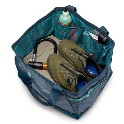 Cotopaxi Allpa 30L Gear Hauler Tote showing inside with cycling shoes, U-lock, and sealant bottle in mesh pockets.