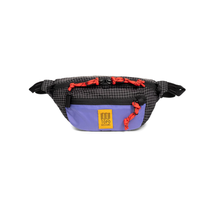 Topo Designs Mountain Waist Pack in black grid pattern with a purple front pocket, red zipper pulls, and yellow brand logo.