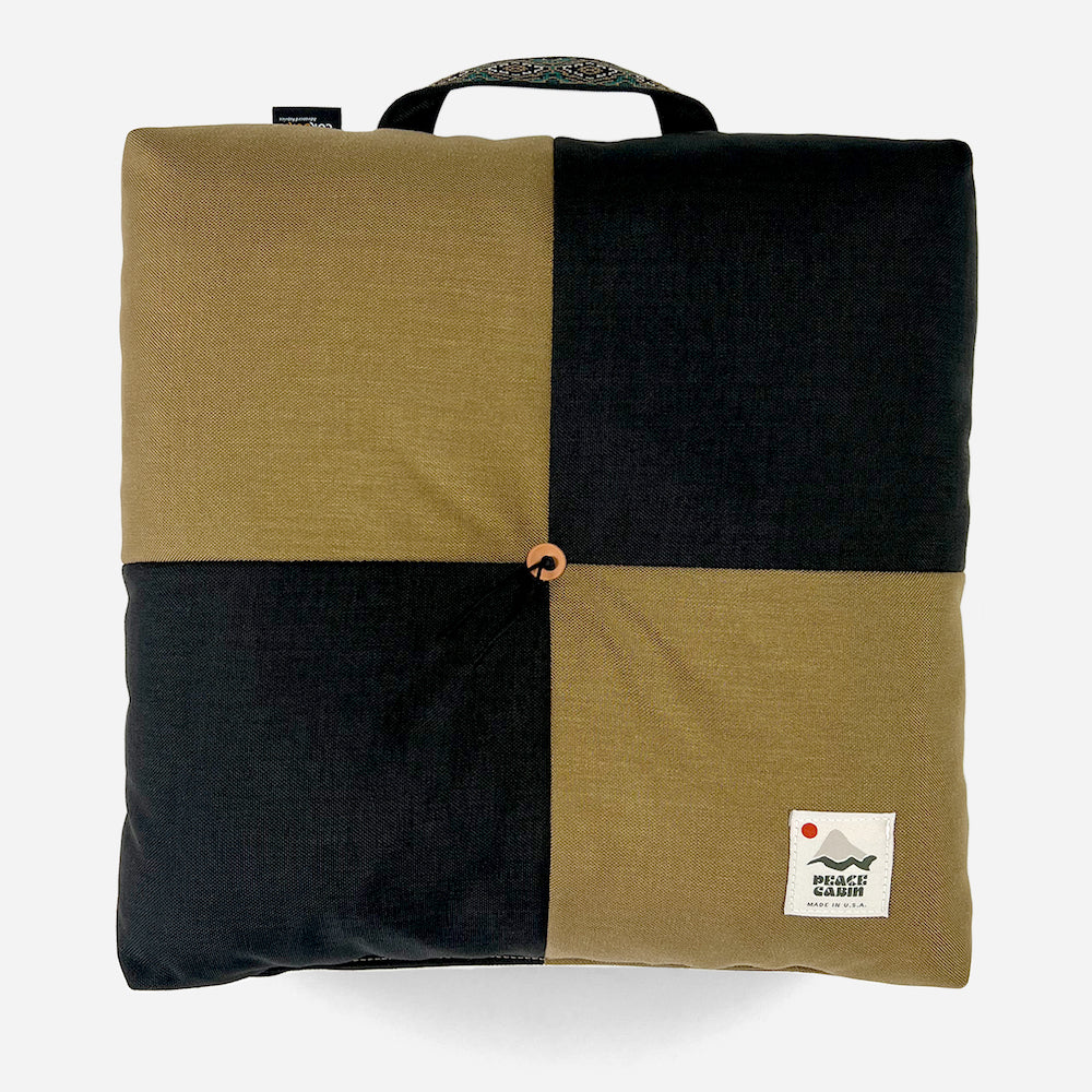 Wanderer 'QUAD' Outdoor Cushion by Media Mercantile, black and olive green checkerboard design with handle.