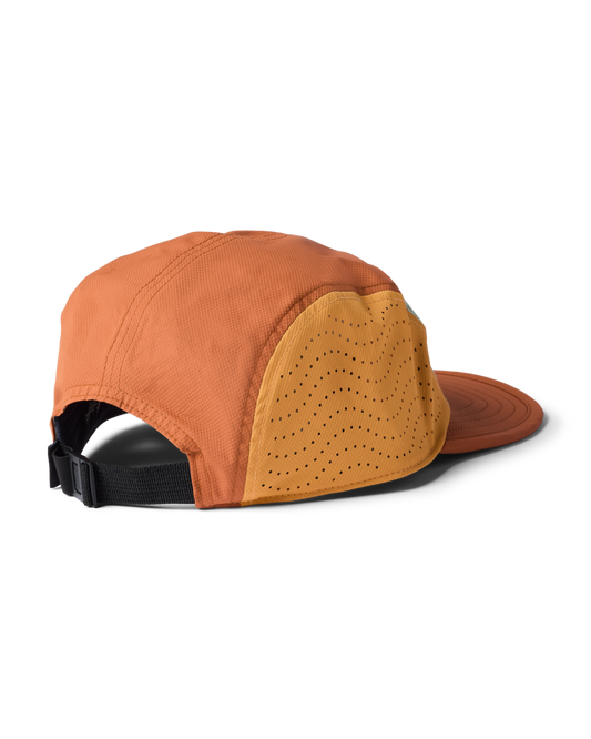 Cotopaxi Tech Plus 5-Panel Hat, side view showing orange fabric, perforated yellow panel, and black adjustable strap.