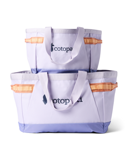 Two lavender Cotopaxi Allpa 60L Gear Hauler Tote bags, stacked, with orange accents and a purple base.