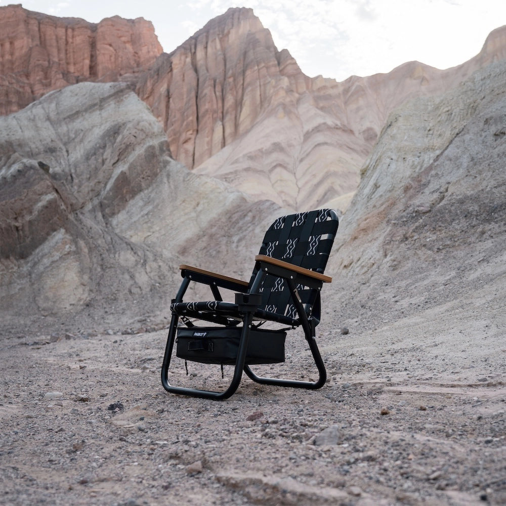 PARKIT Voyager Outdoor Chair in black and white pattern with wooden armrests, set in a desert landscape with mountains.