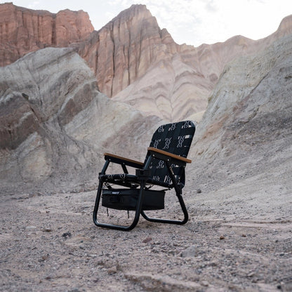PARKIT Voyager Outdoor Chair in black and white pattern with wooden armrests, set in a desert landscape with mountains.