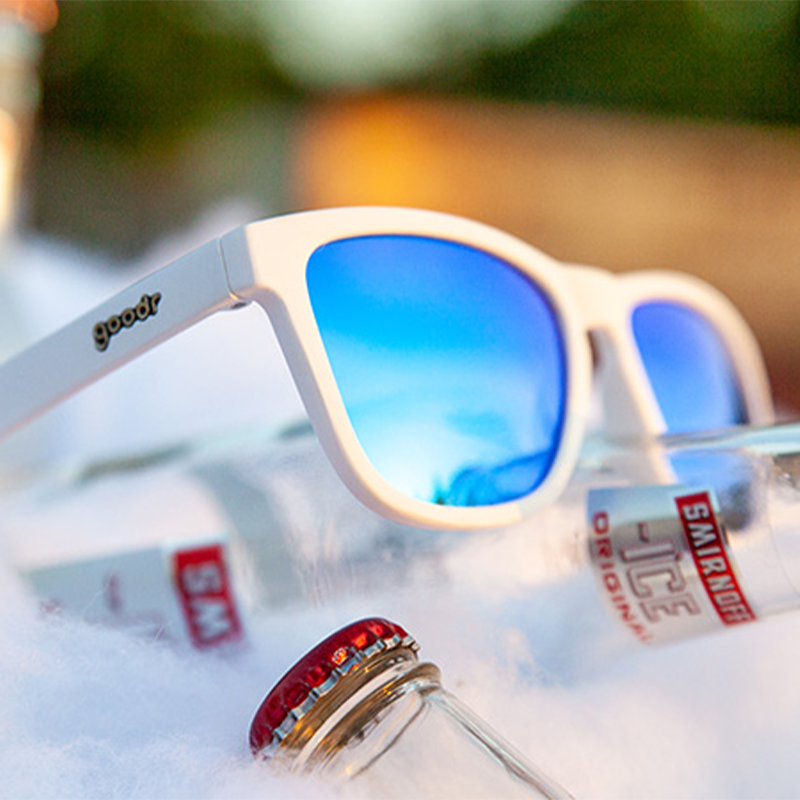 Iced by Yetis goodr sunglasses in white with reflective blue lenses, among Smirnoff Ice bottles and frost.