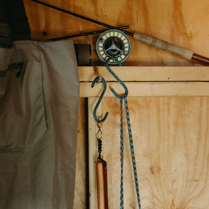 Media Mercantile Utility Hanging Hooks 4 Pack holding rope, next to fishing gear and waders on a wooden wall.