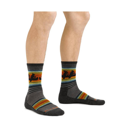 Men's Willoughby Micro Crew Darn Tough socks, grey with colorful stripes and animal designs on a man's legs.