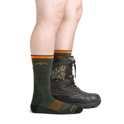 Darn Tough Men's Hunting Boot Midweight Socks in green, shown on feet, one foot with a brown camouflage hunting boot.