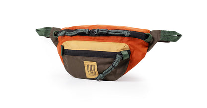Topo Designs Mountain Waist Pack in orange, tan, brown, and green with zippers and cord detailing on a white background.