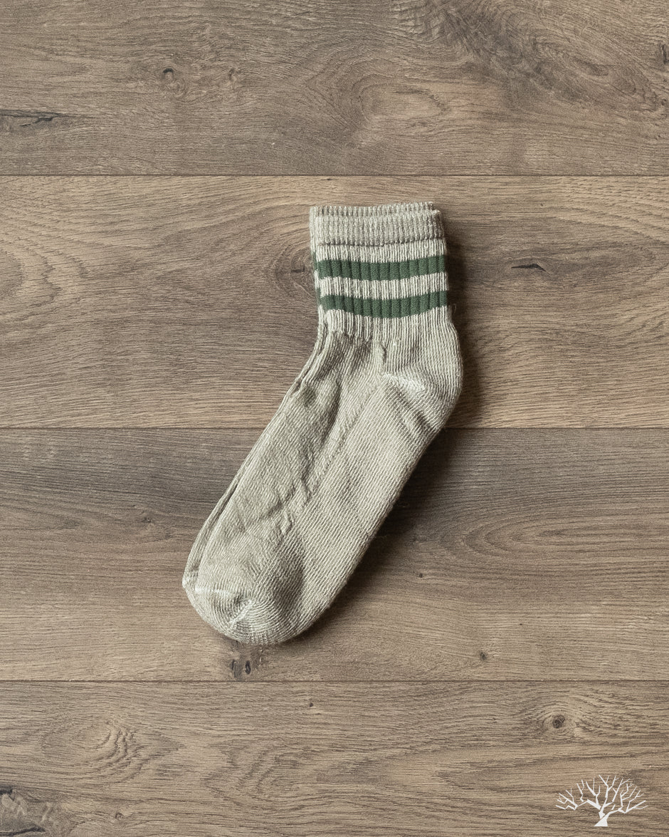 American Trench Merino Activity Quarter Crew sock, light gray with green stripes, on a wooden floor.