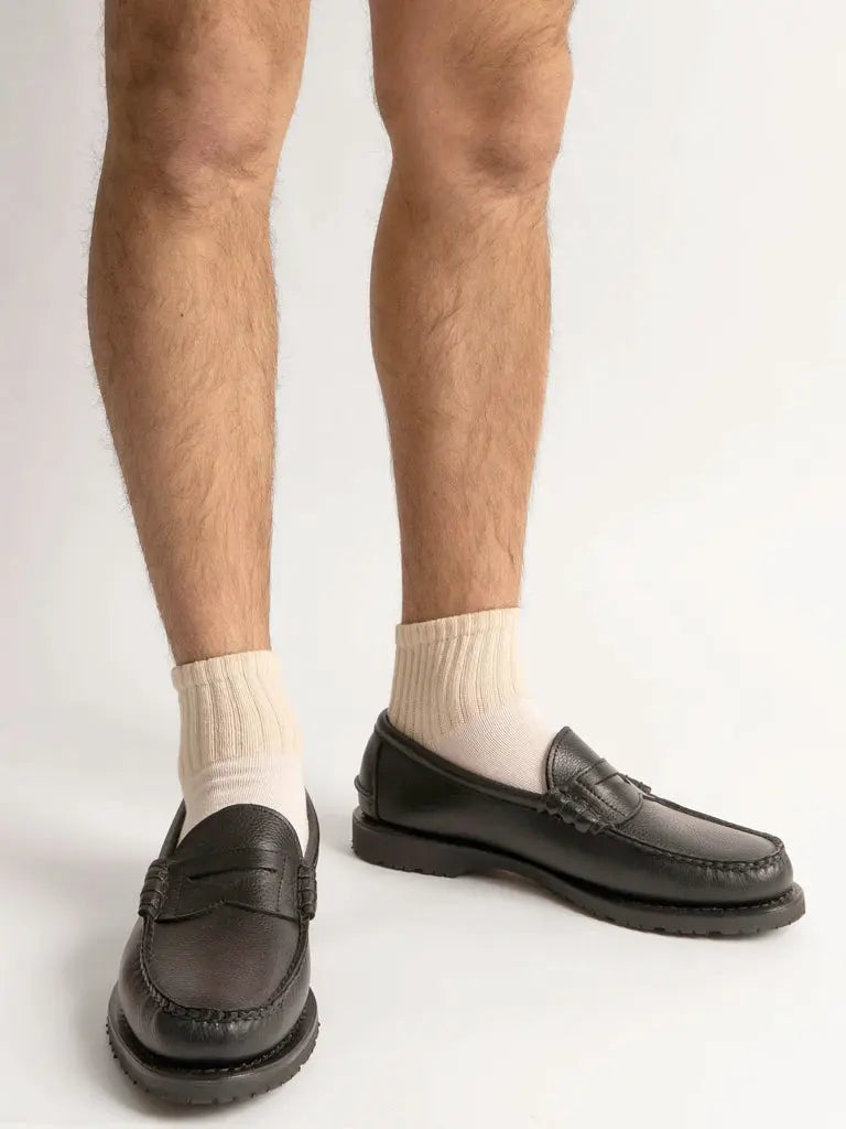 Close-up of a person wearing American Trench The Solids Quarter Crew socks and black leather loafers.