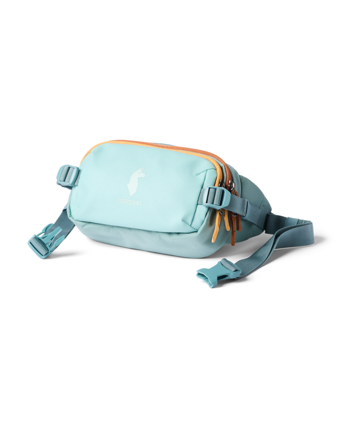 Cotopaxi Allpa X 1.5L Hip Pack in a serene light blue color, featuring orange zipper pulls and an adjustable waist strap.