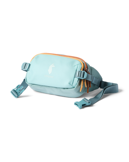 Cotopaxi Allpa X 1.5L Hip Pack in a serene light blue color, featuring orange zipper pulls and an adjustable waist strap.