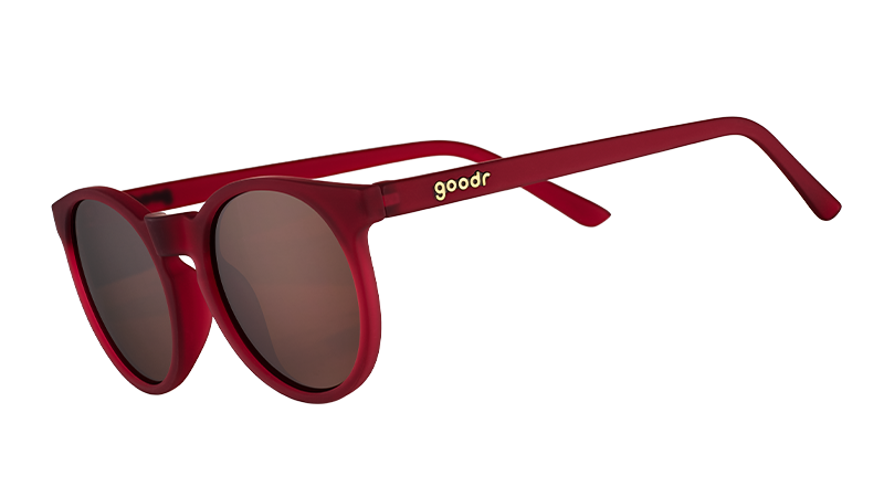 I'm Wearing Burgundy? goodr sunglasses featuring round, matte red frames and brown polarized lenses, angled.