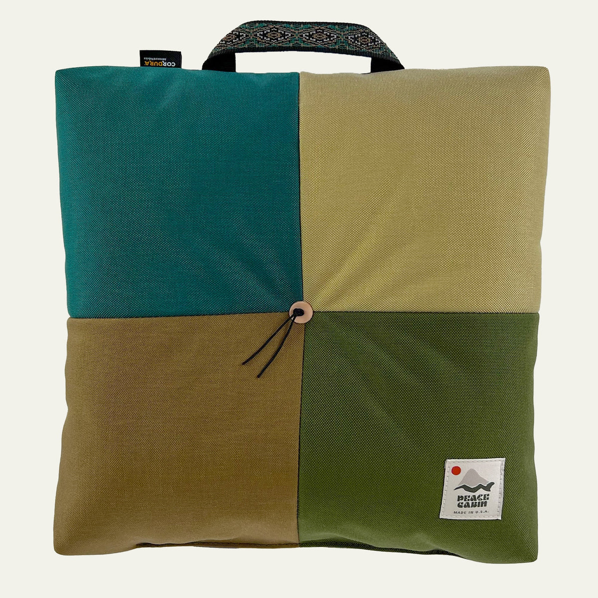 Wanderer 'QUAD' Outdoor Cushion by Media Mercantile, four panels in teal, tan, olive, brown, with handle and button.