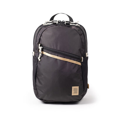 Topo Designs Commuter Backpack in black with tan accent strap, front zipper pocket, and Topo Designs logo.