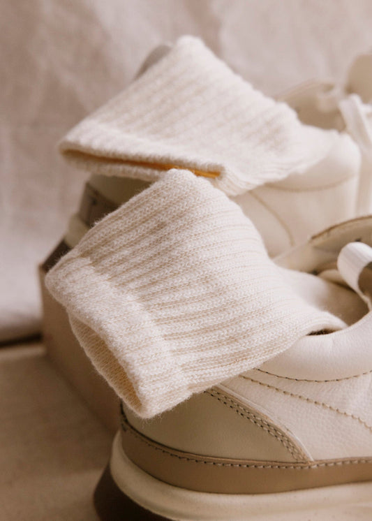 American Trench Women's Statement Ankle Cashmere socks in ivory, soft ribbed knit peeking from white sneakers.