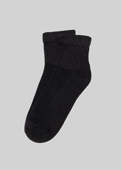 A pair of black American Trench The Solids Quarter Crew socks, featuring ribbed cuffs, on a light grey background.
