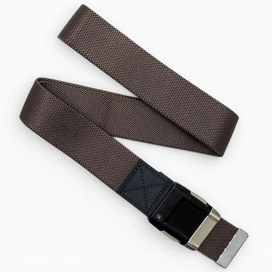 Arcade Belts Motion Stretch Belt in brown, with a woven fabric and black and silver buckle, laid flat on a white surface.