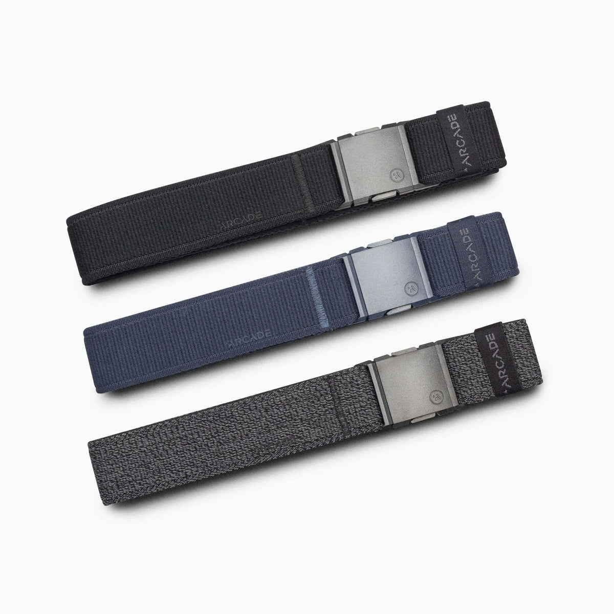 Arcade Belts Atlas Stretch Belt in black, blue, and gray with metallic buckles, arranged diagonally.