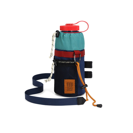 Topo Designs Mountain Hydro Sling in blue, green, and red, holding a water bottle with a red cap. Features a shoulder strap and mesh pocket.