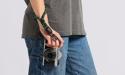 NocLoc Approach Wrist Loop by Nocs Provisions in green and black on a person's wrist, holding a camera.