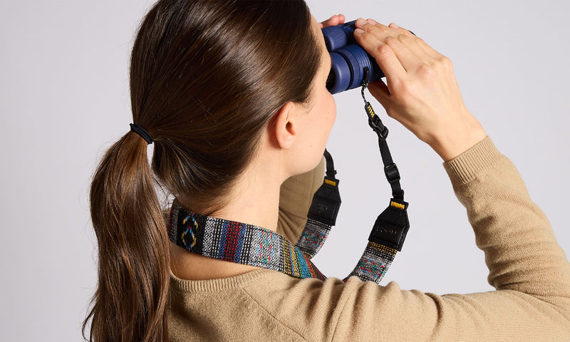 Nocs Provisions NocLoc Woven Tapestry Neck Strap on a woman's neck as she looks through blue binoculars.