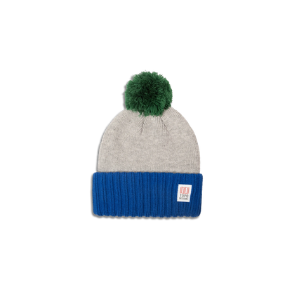 Topo Designs Pompom Beanie featuring a grey knit top, blue ribbed brim, and a fluffy green pompom.