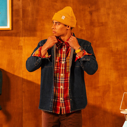 Topo Designs Waffle Knit Beanie in yellow worn by a man in a red plaid shirt and denim jacket, adjusting his collar.