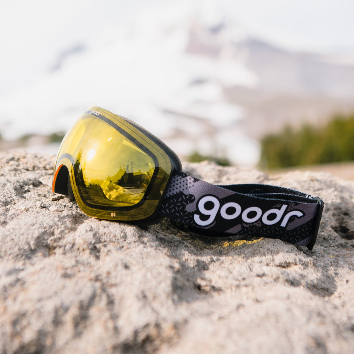 Yellow Jacket's Yard Sale | goodr ski goggles with yellow lenses and black strap on a rock, mountain background.